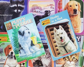 Könnte beinhalten: Eine Sammlung von Kinderbüchern mit Tierillustrationen. Titel sind u.a. "Raccoons on the Roof", "Puppy in a Puddle" und "Husky in a Hut". Die Bücher haben farbenfrohe Cover mit Bildern verschiedener Tiere.