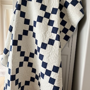 May include: A white and navy blue quilt with a checkered pattern and a circular quilting design.