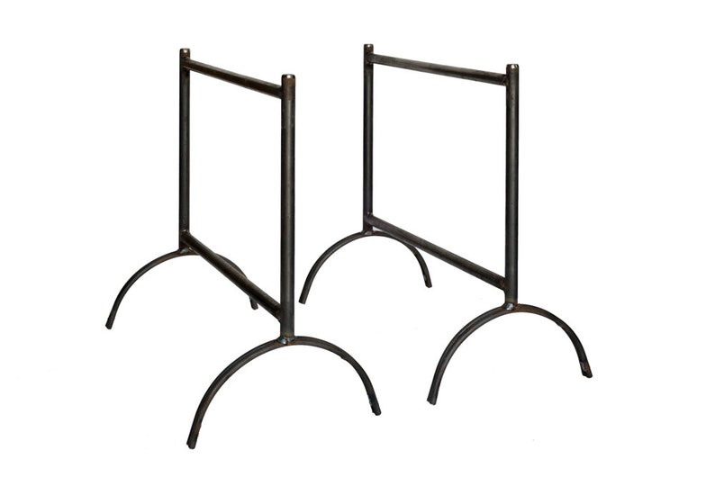 May include: Two black metal table bases with arched legs. The bases are made of sturdy metal and have a simple, industrial design.
