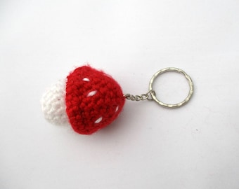 May include: A red and white crocheted mushroom keychain with a silver metal ring.