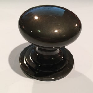May include: A black door knob with a round, polished top and a base with a decorative ring.