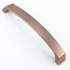 May include: A brushed copper cabinet pull with a slightly curved shape and squared ends.