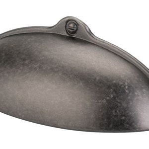 May include: A silver-toned, cup-shaped cabinet pull with a slightly rounded, oval shape. The pull has a distressed finish and features two small, round, silver-toned screws.