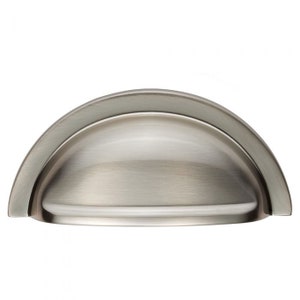 May include: A silver cup-shaped cabinet pull with a bevelled edge.