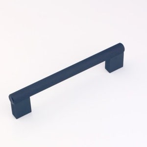 May include: A dark blue metal cabinet pull with a rectangular shape and a slightly rounded edge. The pull has a textured surface.
