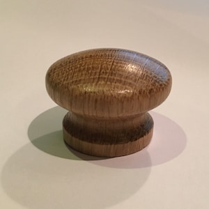 May include: A wooden knob with a rounded top and a cylindrical base. The knob is a light brown colour and has a natural wood grain.