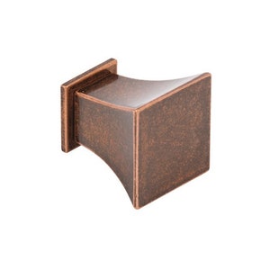 May include: A square-shaped cabinet knob with a slightly flared base. The knob is made of metal and has a distressed copper finish.