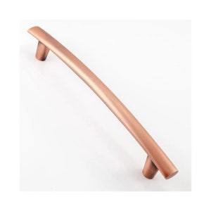 May include: A curved copper cabinet pull with a brushed finish. The pull is approximately 15cm long.