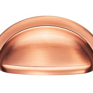 May include: A copper cabinet knob with a rounded, arched shape. The knob has a brushed finish.