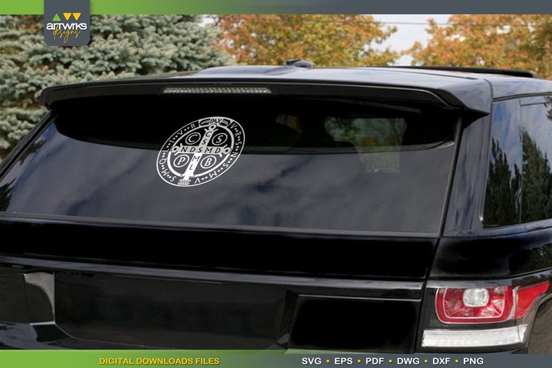 May include: A black car with a white Saint Benedict medal sticker on the back window. The medal features a cross with the letters 'C.S.S.M.L.  N.D.S.M.D.' around it.