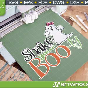 May include: A green cutting mat with a white ghost with a pink bow and the text "Shake your Boo-ty" in black, orange, and green lettering.