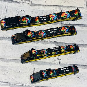 May include: Four colourful dog collars with a black background and yellow trim. The collars feature a tropical leaf print and the text "Fur the Love of Toys".