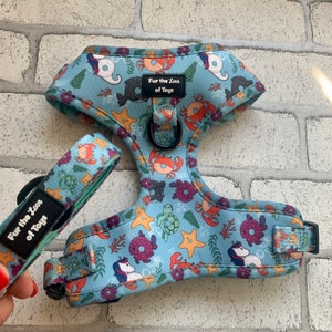 May include: A blue dog harness with a sea-themed pattern featuring seahorses, starfish, crabs, and seashells. The harness has a matching leash with the text "Fur the Love of Toys" on it.