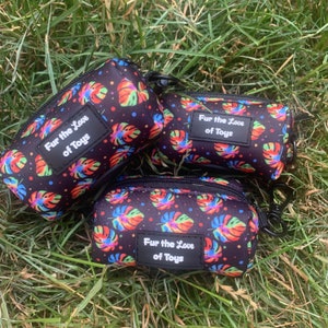 May include: Three black zippered pouches with a colourful tropical leaf pattern and white polka dots. Each pouch has a black label with the text "Fur the Love of Toys".
