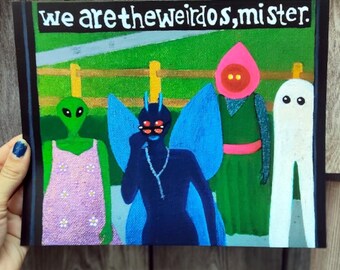 Könnte beinhalten: Ein farbenfrohes Gemälde mit vier skurrilen Figuren: einem grünen Alien, einer blauen feenartigen Kreatur, einer pinkfarbenen Figur und einem weißen geisterhaften Charakter. Das Gemälde trägt den Text "we are the weirdos, mister." Der Hintergrund ist grün und blau.