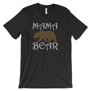 以下が含まれることがあります： 黒いTシャツに白い文字で「ママベア」と書いてあり、茶色の熊のシルエットが描かれている。