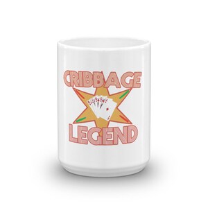 Pode incluir: Caneca de caf&eacute; de cer&acirc;mica branca com uma estrela dourada e o texto "Cribbage Legend" em laranja. A estrela tem cartas de jogo dentro.