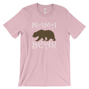 以下が含まれることがあります： ピンクのTシャツに、白い文字で「ママベア」と、茶色のクマのシルエットが描かれています。