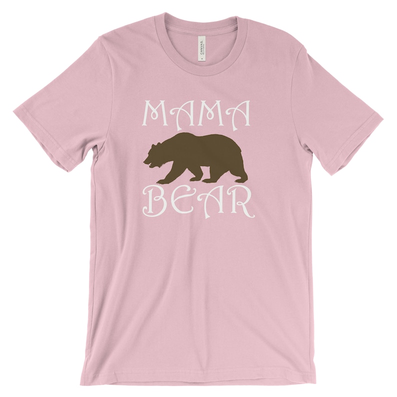 以下が含まれることがあります： ピンクのTシャツに、白い文字で「ママベア」と、茶色のクマのシルエットが描かれています。
