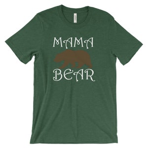 以下が含まれることがあります： 白い文字で「MAMA BEAR」と書いてある緑色の半袖Tシャツ。茶色の熊のシルエットが描かれている。