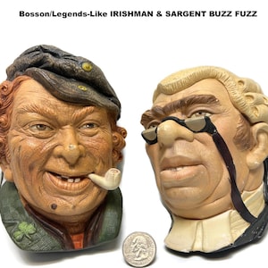 May include: Two vintage ceramic busts, one of an Irishman with a pipe and a green jacket, and the other of a judge with spectacles. The busts are tan, brown, and green, with the text "Bossom/Legends-Like IRISHMAN & SARGENT BUZZ FUZZ" at the top.