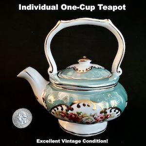 May include: Individual one-cup teapot with a light blue body, white handle, and gold trim. The teapot features a floral design with red and white roses. The text "Individual One-Cup Teapot" and "Excellent Vintage Condition!" are visible.