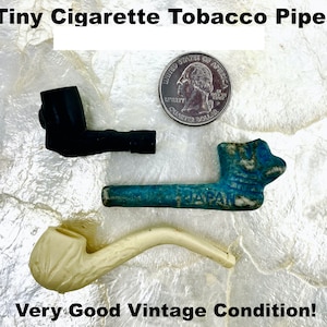 May include: Three tiny cigarette tobacco pipes in black, blue, and off-white, with a quarter for scale. The blue pipe is marked "JAPAN". The text "Tiny Cigarette Tobacco Pipes" and "Very Good Vintage Condition!" are also visible.