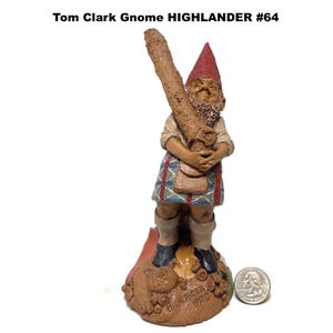 May include: A detailed figurine of a gnome, holding a large log. The gnome wears a red hat, a tan shirt, and a patterned kilt. The base is brown with the text "HIGHLANDER 1993". A quarter is next to the figurine.