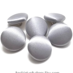 May include: Six silver satin buttons with a textured surface.