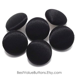 May include: Six black satin buttons, each with a smooth, rounded surface. The buttons are arranged in a cluster on a white background.