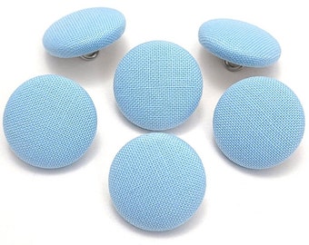 May include: Six light blue fabric covered buttons with a silver shank.