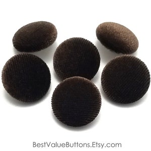 May include: Six brown velvet buttons with a slightly raised texture. The buttons are round and have a smooth, soft surface.