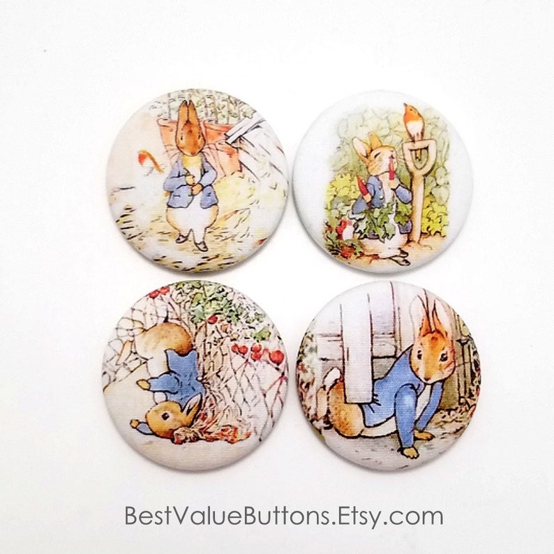 May include: Set of four 1-inch round buttons featuring illustrations of Peter Rabbit from the classic children's book. The buttons feature Peter Rabbit in different scenes from the book, including him in a garden, hiding in a bush, and running away from Mr. McGregor.
