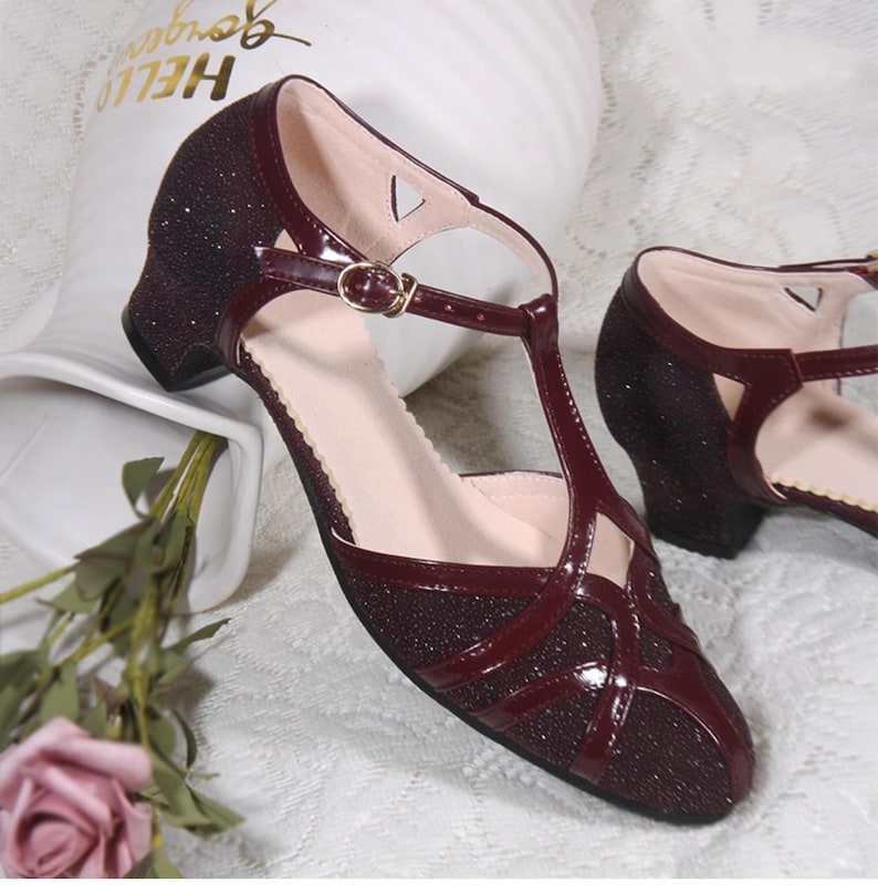 May include: Burgundy glitter heeled sandals with a T-strap and buckle closure.