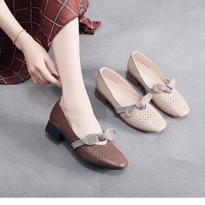Puede incluir: Dos pares de zapatos de tac&oacute;n bajo de color beige y marr&oacute;n con un lazo a cuadros. Los zapatos tienen un dise&ntilde;o perforado y una punta redonda.