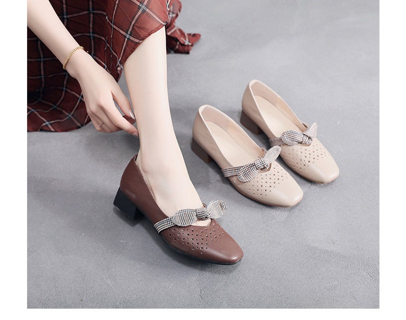 Puede incluir: Dos pares de zapatos de tac&oacute;n bajo de color beige y marr&oacute;n con un lazo a cuadros. Los zapatos tienen un dise&ntilde;o perforado y una punta redonda.