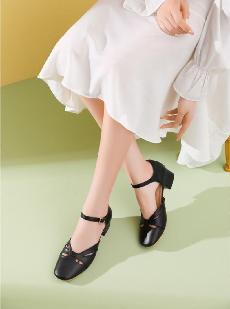 May include: Black leather ankle strap heeled shoes with cutouts and a buckle closure. The shoes have a low block heel.