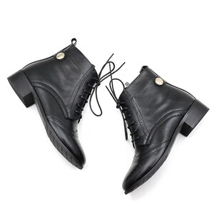 May include: A pair of black leather ankle boots with lace-up closures and a low block heel. The boots have a decorative stitching detail on the toe.