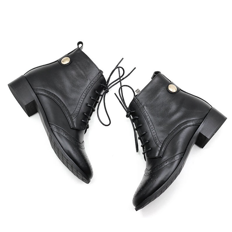 May include: A pair of black leather ankle boots with lace-up closures and a low block heel. The boots have a decorative stitching detail on the toe.