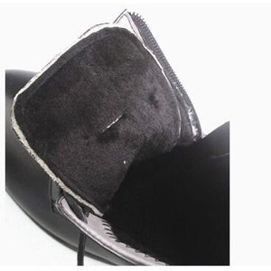May include: Close-up of the inside of a black leather boot with a soft, black lining. The boot has a zipper on the side.