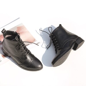 May include: Black leather ankle boots with lace-up closures and a brogue design. The boots have a low block heel.