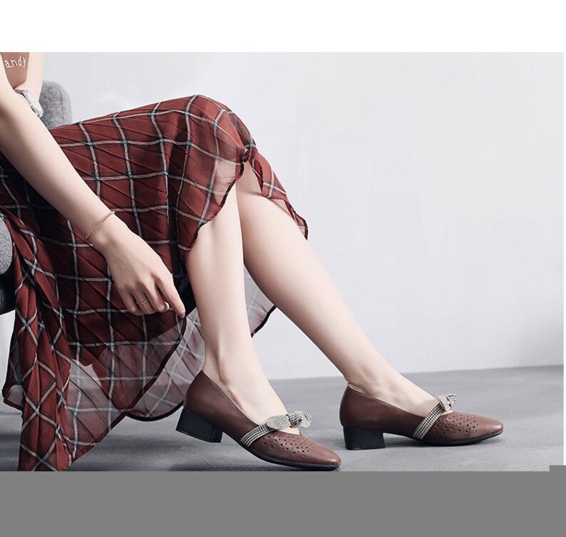 Puede incluir: Zapatos de cuero marr&oacute;n con un peque&ntilde;o lazo y detalles recortados. Los zapatos tienen un tac&oacute;n de bloque bajo.