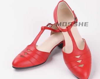 May include: A pair of red leather t-strap heeled shoes with a pointed toe and cut-out detailing. The shoes have a low block heel.