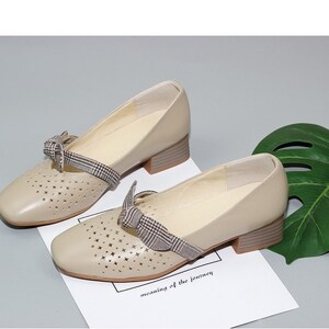 Puede incluir: Zapatos de cuero beige con tac&oacute;n bajo de bloque y detalle de lazo de cuadros. Los zapatos tienen un dise&ntilde;o de corte y son perfectos para la primavera y el verano.