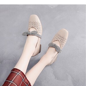Puede incluir: Un par de pisos beige con un lazo a cuadros y un dise&ntilde;o perforado. Los zapatos tienen un tac&oacute;n bajo y una punta redonda.