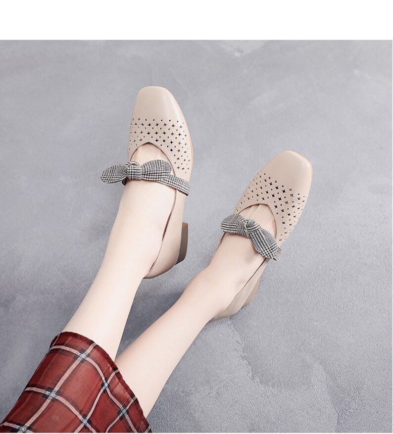 Puede incluir: Un par de pisos beige con un lazo a cuadros y un dise&ntilde;o perforado. Los zapatos tienen un tac&oacute;n bajo y una punta redonda.