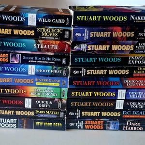 May include: A collection of twenty paperback books by Stuart Woods stacked in two columns. The spines feature the author's name, titles including Wild Card, Naked Greed, Strategic Moves, Lucid Intervals, Stealth, Loitering with Intent, and others.