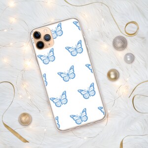 Puede incluir: Una funda de tel&eacute;fono transparente con fondo blanco y un patr&oacute;n repetitivo de mariposas azules.