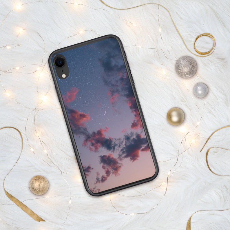 May include: A black phone case with a pink and blue sky with stars and a crescent moon printed on it.