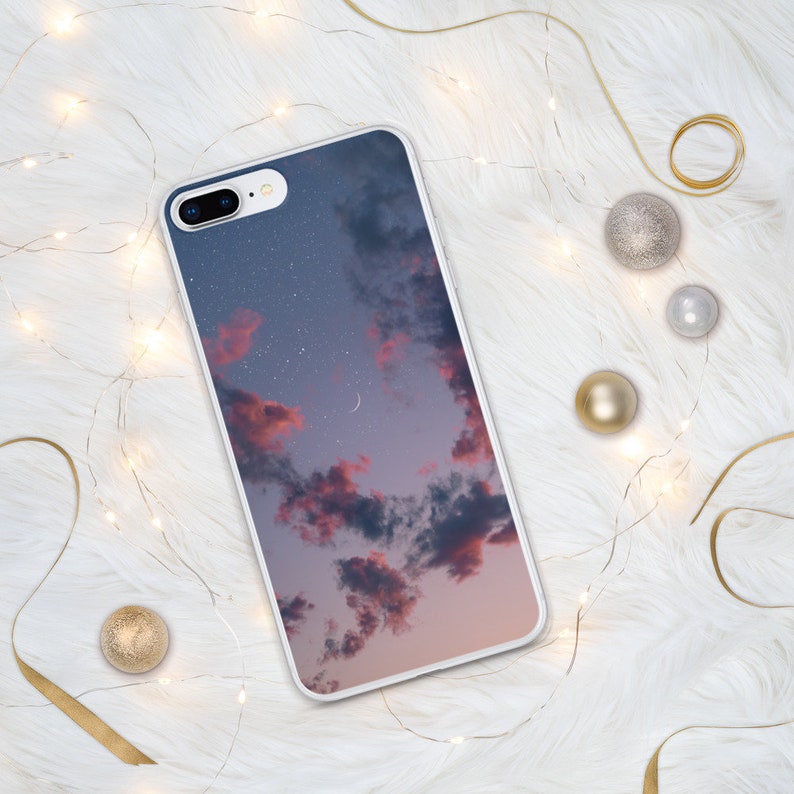 May include: A white phone case with a pink and blue sky with clouds and stars printed on it.